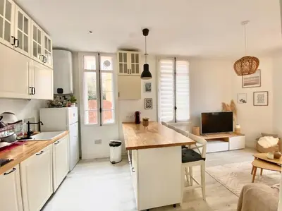a kitchen with white cabinets and a wooden counter top at Joli appartement au calme à 10 min à pied des Marches et des plages in Cannes