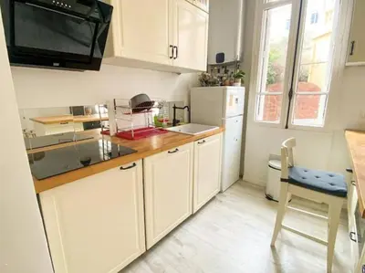 a kitchen with a refrigerator and a table and a chair at Joli appartement au calme à 10 min à pied des Marches et des plages in Cannes