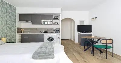 a room with a bed and a kitchen with a washing machine at L'Hippocampe - Studio - Croisette - Proche Palais in Cannes