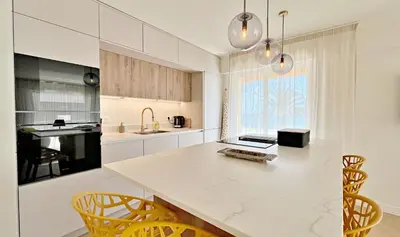 a kitchen with a white counter and yellow chairs at Une véritable perle 342L HUI in Cannes