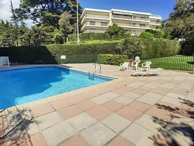 a swimming pool with two chairs and a building at Superbe studio, piscine 330L Giov in Cannes
