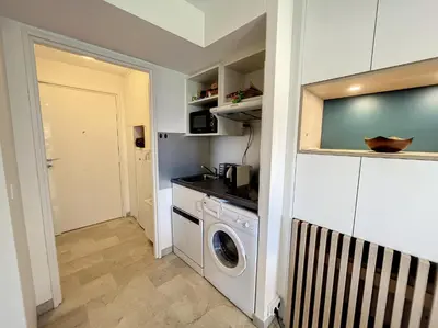 a kitchen with a washer and dryer in a room at Superbe studio, piscine 330L Giov in Cannes