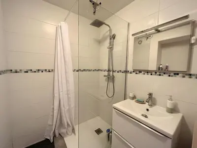 a white bathroom with a shower and a sink at Superbe studio, piscine 330L Giov in Cannes