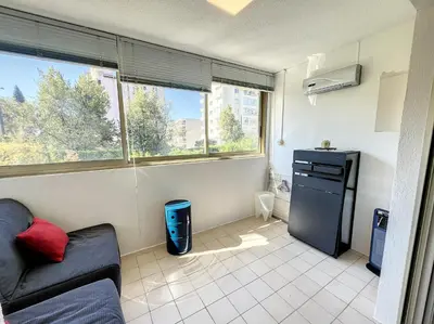 a living room with a couch and a refrigerator at Superbe studio, piscine 330L Giov in Cannes