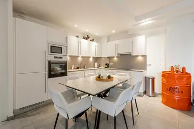 a kitchen with white cabinets and a table and chairs at Modern 1 bedrm apt with balcony - Cannes-Croisette in Cannes