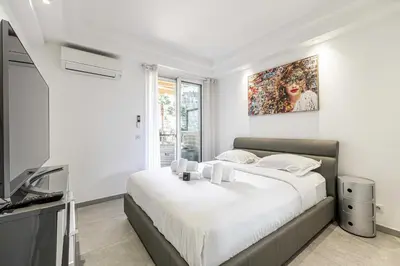 a white bedroom with a large bed and a television at Modern 1 bedrm apt with balcony - Cannes-Croisette in Cannes