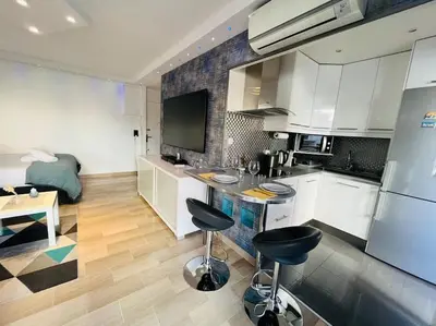 a kitchen with white cabinets and black stools in it at Studio premium St Louis - emplacement idéal in Cannes