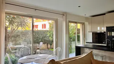 a kitchen and living room with a table and a glass door at L'Azur - Apt de Standing - Piscine - Parking in Le Cannet