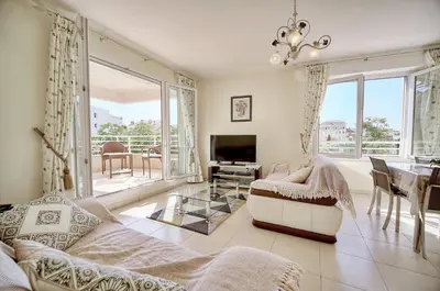 a living room with a couch and a table and a television at Spacieux 2 chambres TERRASSE, PARKING proche CENTRE VILLE A2B237 in Cannes