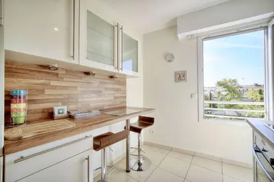 a kitchen with white cabinets and a counter with a window at Spacieux 2 chambres TERRASSE, PARKING proche CENTRE VILLE A2B237 in Cannes