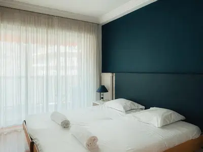 a bedroom with a large white bed with a blue wall at Intuition - 2 personnes - Le Fragonard in Cannes
