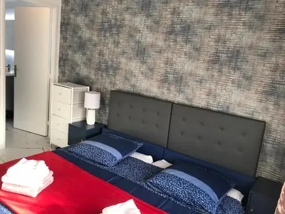a bedroom with a large bed with blue and red sheets at T2 Vallombrosa Terrasse Parking in Cannes
