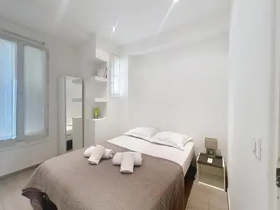 a white bedroom with two towels on a bed at Commandant André in Cannes