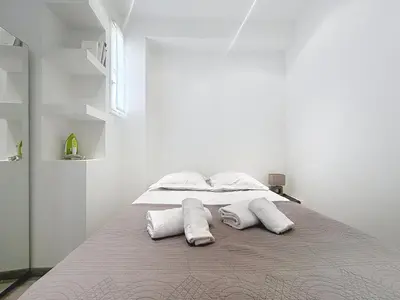 a white bedroom with a bed with two pillows at Commandant André in Cannes