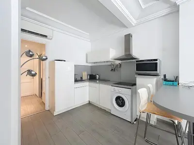 a white kitchen with a washing machine and a table at Commandant André in Cannes