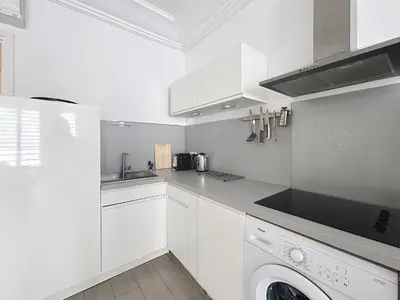 a kitchen with white cabinets and a washer and dryer at Commandant André in Cannes