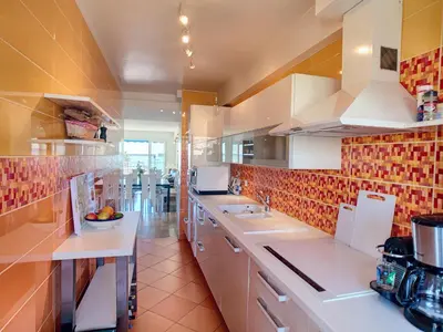 a kitchen with white counters and red tiles on the wall at Belle terrasse vue mer , proche plages 223L FOV in Cannes