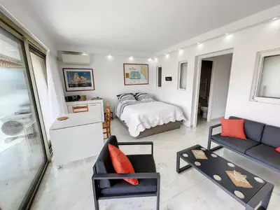 a bedroom with a bed and a couch and a table at STUDIO MIDI MAGRET Cannes in Cannes