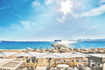 a beach with chairs and umbrellas and the ocean at Nice studio for two close to the beaches of Cannes in Cannes
