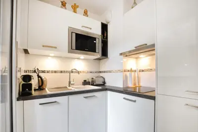 a kitchen with white cabinets and a microwave at Nice studio for two close to the beaches of Cannes in Cannes