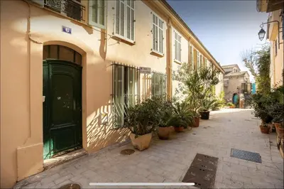 a building with a green door and potted plants on a street at Le Suquet - Château - Palais - Seaview - WIFI in Cannes