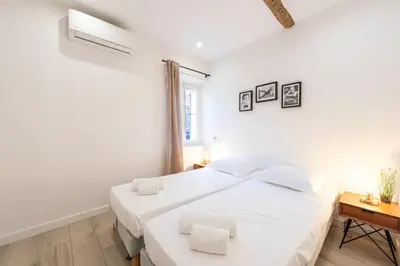 a white bedroom with a large bed and a desk at 3P Central Cannes Suquet in Cannes