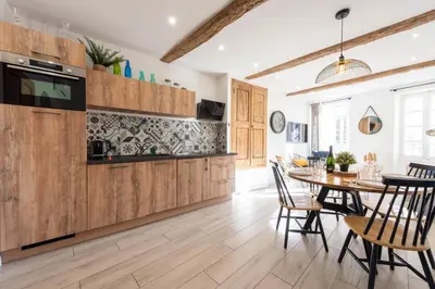 a kitchen with wooden cabinets and a table with chairs at 3P Central Cannes Suquet in Cannes