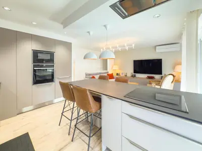 a kitchen and living room with a counter and chairs at Le Marcellin by Winsome Destination in Cannes