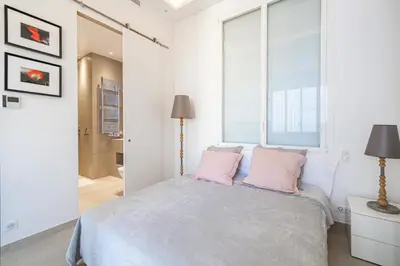 a white bedroom with a bed with pink pillows at REF 1975 - Cannes Center - Croisette in Cannes
