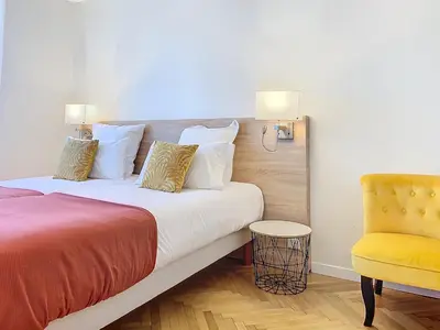 a bedroom with a bed and a yellow chair at 3p Quai St Pierre - 348L Alexa in Cannes