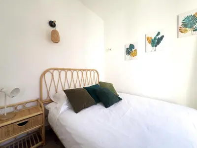a bedroom with a bed with white sheets and green pillows at Calme et centrale avec balcon ensoleillé in Le Cannet