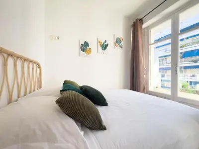 a bed with two pillows on it with a window at Calme et centrale avec balcon ensoleillé in Le Cannet
