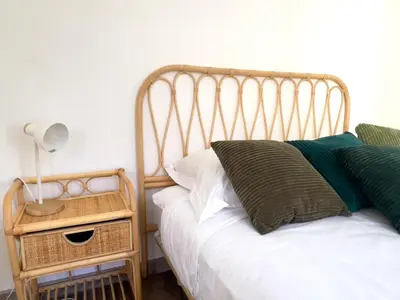 a bed with a wooden headboard next to a night stand at Calme et centrale avec balcon ensoleillé in Le Cannet