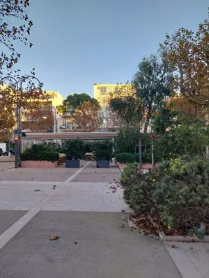 a park with trees and bushes and a building at Palm beach Cannes La Brise in Cannes