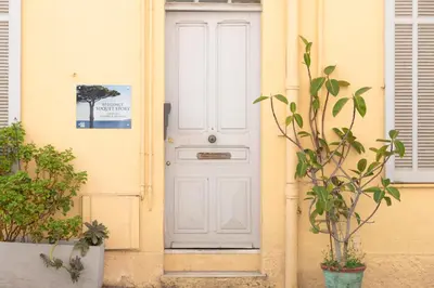 a white door on a yellow building with a plant at cœur historique de cannes entre palais et mer in Cannes