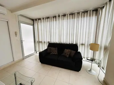 a living room with a black couch in front of a window at Two bedroom apartment on a high floor in the center of Cannes a few steps from the Croisette beaches - 2229 in Cannes