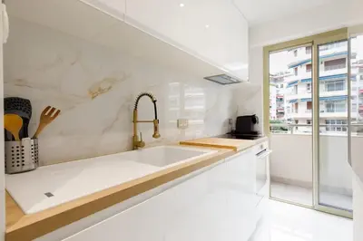 a white kitchen with a sink and a window at Carlton area superb 1 bedroom in Cannes