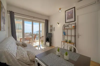 a room with a balcony with a table and a glass door at FRGK Fauvettes Apartment Terrace, Parking, AC & Ultra-Fast Wi-Fi in Cannes