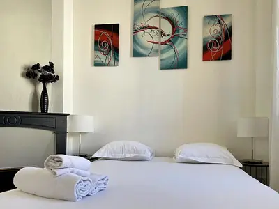 a bedroom with two beds and four paintings on the wall at Viva Riviera - 10 Rue Florian in Cannes