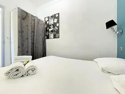 a bedroom with a white bed and a chair at Viva Riviera - 10 Rue Florian in Cannes