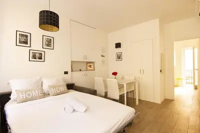 a white bedroom with a bed and a dining room at Magnifique T2 au cœur de Cannes in Cannes