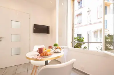 a dining room with a table and chairs and a window at le suquet entre palais et des plages in Cannes