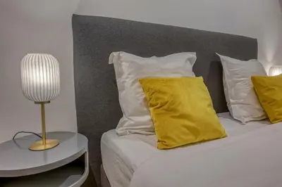 a bed with yellow pillows and a table with a lamp at Loft Croisette Standing Presta in Cannes