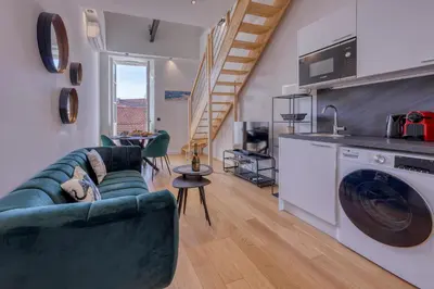 a living room with a green couch and a kitchen at Loft Croisette Standing Presta in Cannes