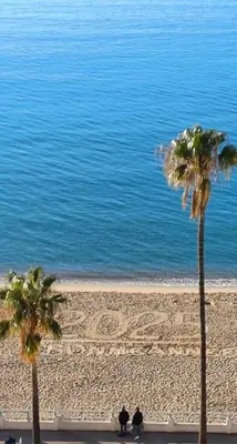two people sitting on a beach with palm trees at Cannes SEASIDE BEACHFRONT bord de mer in Cannes