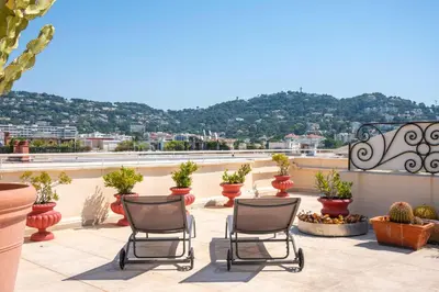 two chairs sitting on a patio with potted plants at Cannes - Roof terrace for rent in Cannes