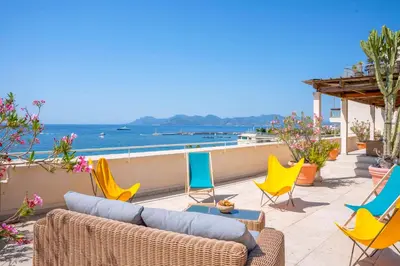 a patio with chairs and a couch and the ocean at Cannes - Roof terrace for rent in Cannes