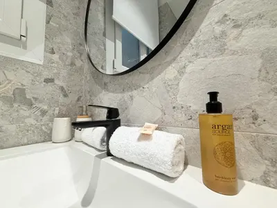 a bathroom sink with a bottle of soap and a mirror at 9A - APARTMENT FACING PORT & Town Hall in Cannes