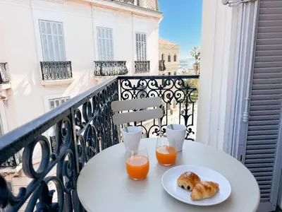 a table with two glasses of orange juice and biscuits on a balcony at 12B - APARTMENT FACING PORT & Town Hall in Cannes