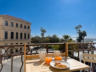 a table with a plate of food on a balcony at 4A - APARTMENT FACING PORT & Town Hall in Cannes